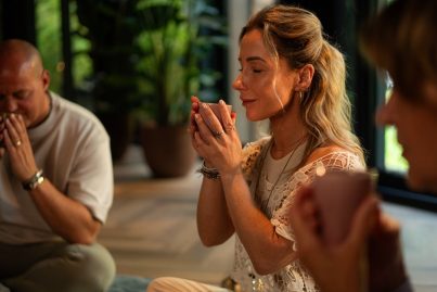 Vrouw houdt een kop cacao vast tijdens een ceremonie, terwijl ze een intentie uitspreekt in een rustgevende omgeving