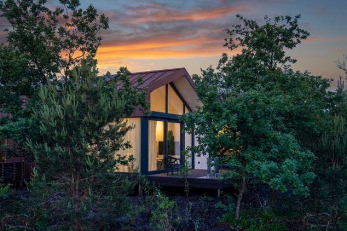 Luxe vakantiewoning bij avond, sfeervol verlicht en omgeven door de natuur van de Veluwe.